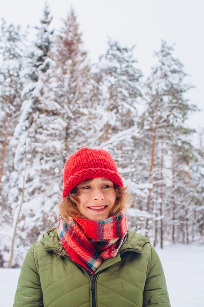 Portret van een meisje in een rode hoed en sjaal in het winterbos