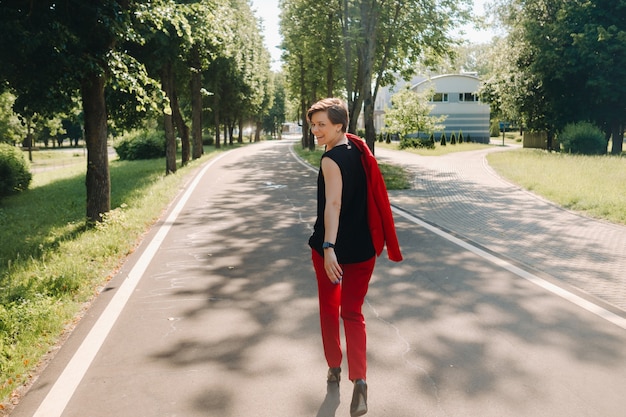 Portret van een meisje in een rood pak dat in het steegje van het park staat.