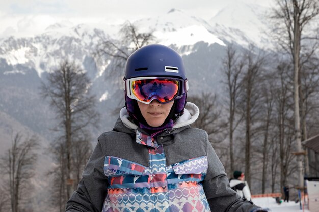 Portret van een meisje in snowboardkleding tegen een achtergrond van bergen