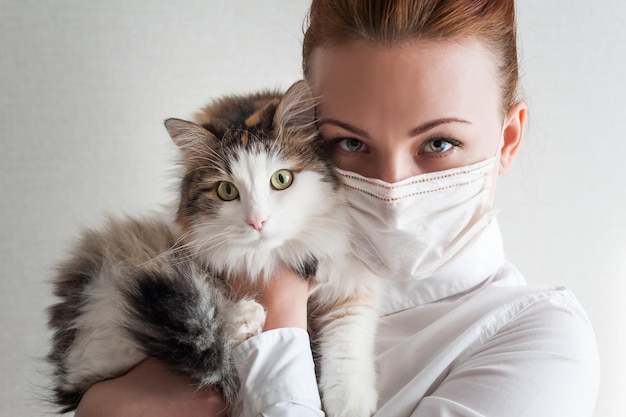 Portret van een meisje met een medisch masker Ze houdt een kat vast Close upxA