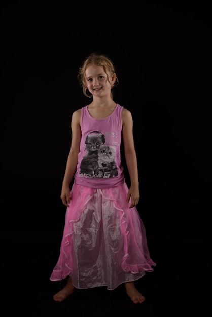 Foto portret van een meisje met een roze jurk op een zwarte achtergrond