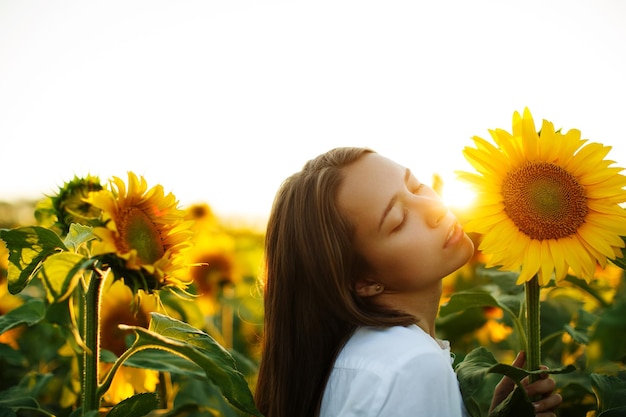 portret van een meisje met een zonnebloem in een veld van zonnebloemen op een zonnige dag warm herfstconcept