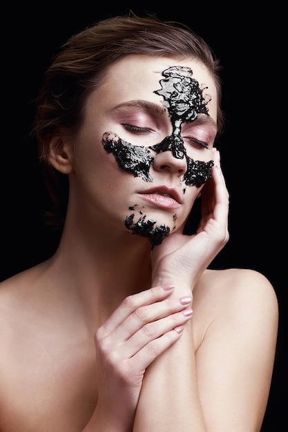 Portret van een meisje met een zwart cosmetisch masker op haar gezicht