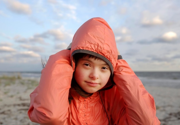 Portret van een meisje met het syndroom van down glimlachend op de achtergrond van de zee