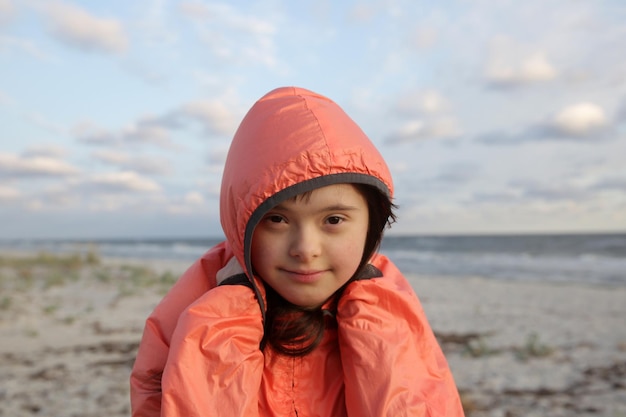 Portret van een meisje met het syndroom van down glimlachend op de achtergrond van de zee