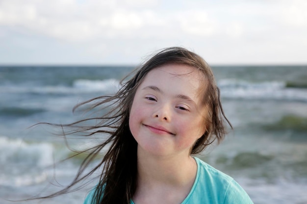 Portret van een meisje met het syndroom van down glimlachend op de achtergrond van de zee