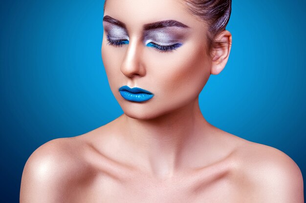 Foto portret van een meisje op een blauwe achtergrond met professionele make-up