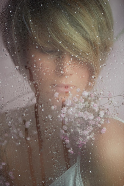 Portret van een meisje op een roze achtergrond met bloemen Tederheid en vrouwelijk De sfeer van schoonheid en de gezondheid van vrouwen Kort kapsel blond haar