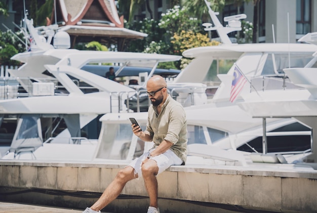 Portret van een mode jonge man die zich voordeed op de achtergrond van de jachthaven en yahts