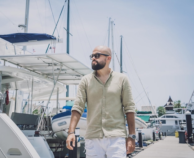 Portret van een mode jonge man die zich voordeed op de achtergrond van de jachthaven en yahts