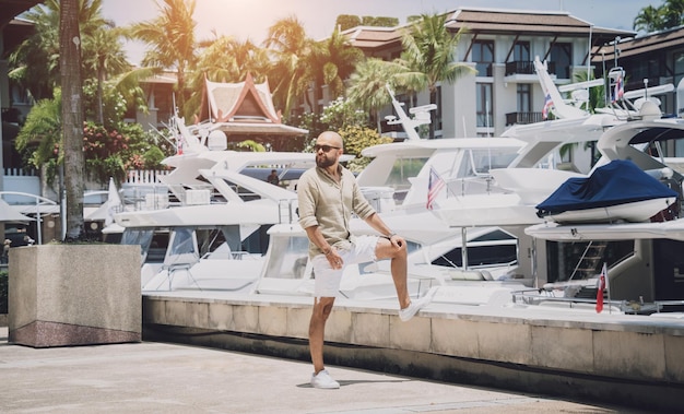 Portret van een mode jonge man die zich voordeed op de achtergrond van de jachthaven en yahts