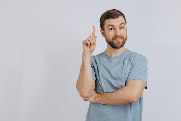 Portret van een moderne bebaarde man van middelbare leeftijd in een blauwe t-shirt die iets op een witte achtergrond laat zien