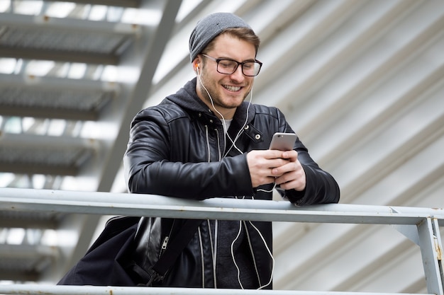 Portret van een moderne jonge man die zijn mobiele telefoon op straat gebruikt.