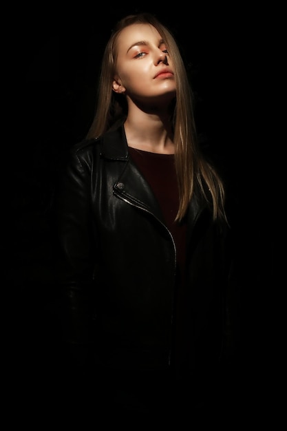 Portret van een modieuze vrouw die tegen een zwarte achtergrond staat