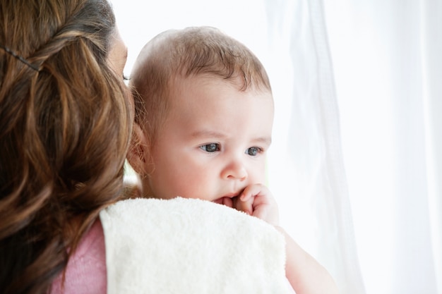 Portret van een moeder die haar baby na het bad thuis vertroetelt