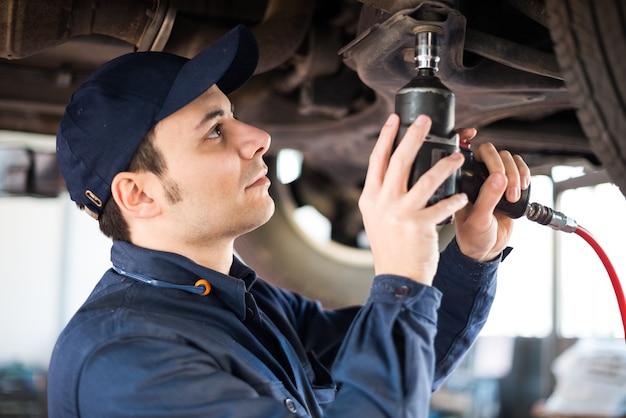 Portret van een monteur die een auto in zijn garage herstelt