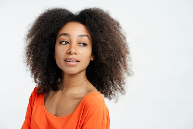 Portret van een mooi Afro-Amerikaans modemodel, gekleed in een casual bruin t-shirt, wegkijkend poseren geïsoleerd op witte achtergrond Concept van stijlvolle levensstijl