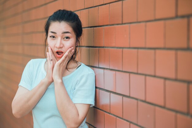 Portret van een mooi aziatisch chic meisje poseert voor het nemen van een foto op bakstenen muur