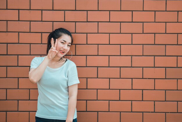 Portret van een mooi aziatisch chic meisje poseert voor het nemen van een foto op bakstenen muur