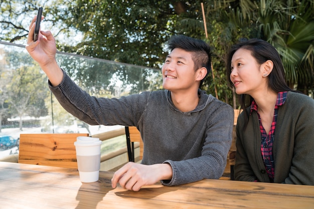 Portret van een mooi Aziatisch paar dat goede tijd heeft en een selfie met mobiele telefoon in coffeeshop neemt