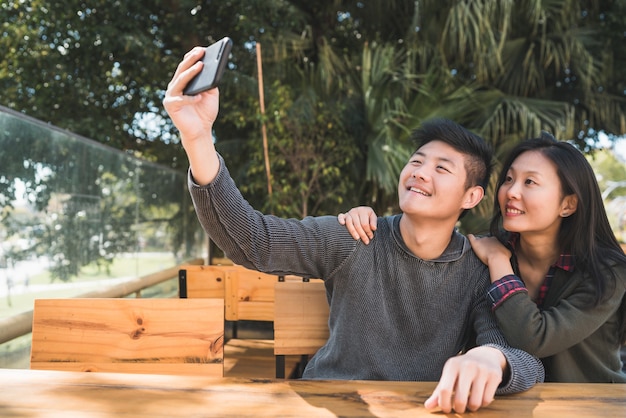 Portret van een mooi Aziatisch paar dat goede tijd heeft en een selfie met mobiele telefoon in coffeeshop neemt.