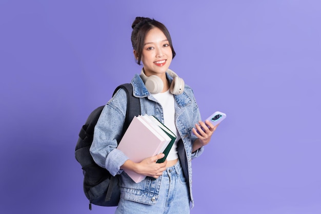 Portret van een mooi Aziatisch schoolmeisje met een rugzak op een paarse achtergrond