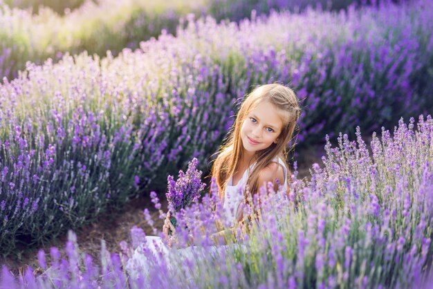 Portret van een mooi babymeisje in een lavendelgebied. Zomerfoto in paarse kleuren.