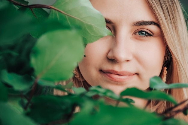 Foto portret van een mooi blond meisje met natuurlijke schoonheid in een groene bladeren bomen. kopiëren, lege ruimte voor tekst
