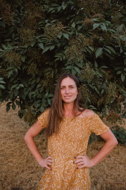 portret van een mooi donkerharig meisje met blauwe ogen in een gele jurk in de natuur