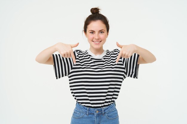 Portret van een mooi glimlachend jong vrouwelijk model dat reclame toont met vingers naar beneden