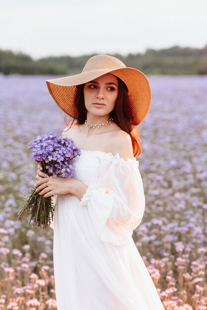 Portret van een mooi jong meisje in een witte jurk in een bloeiend veld van de provence