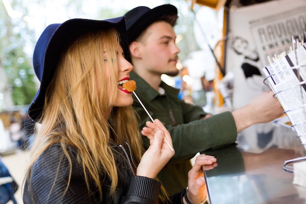 Portret van een mooi jong stel dat een bezoek brengt aan de eetmarkt in de straat.