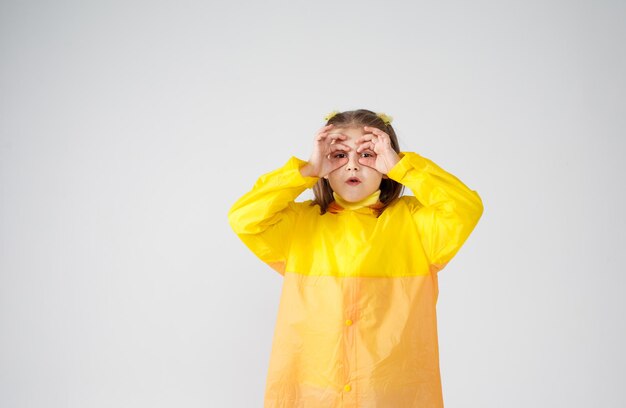 Portret van een mooi klein meisje in een gele regenjas op isoleren op een witte achtergrond.