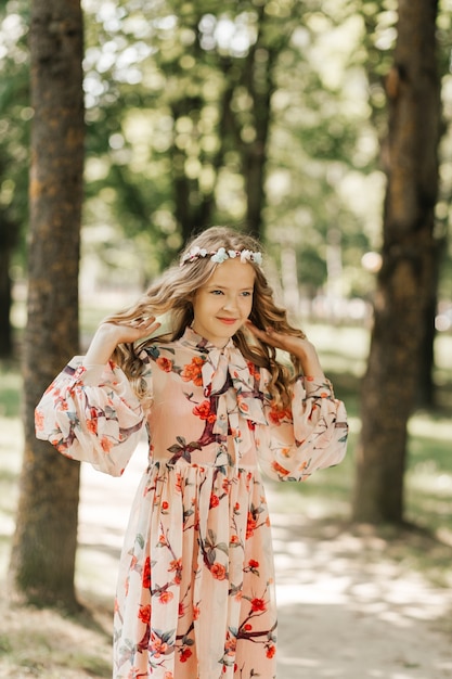 Portret van een mooi klein meisje met lang blond haar in het park in de zomer