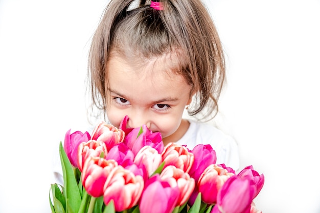 Portret van een mooi lachend meisje met lentetulpen op een witte achtergrond