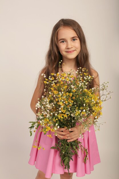 portret van een mooi langharig meisje met wilde herfstbloemen in haar handen