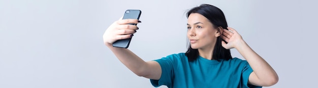 Portret van een mooi meisje dat een selfie neemt die over grijze achtergrond wordt geïsoleerd