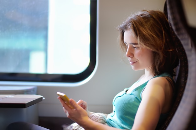 Portret van een mooi meisje dat op de telefoon in een treinauto communiceert