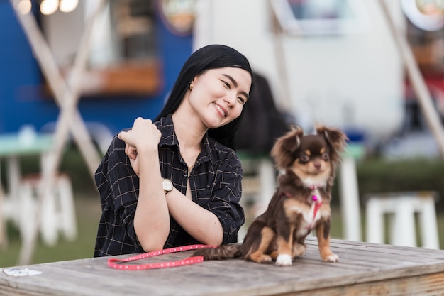 Portret van een mooi meisje dat speelt met haar mooie puppy buiten in het openbare park. Kleine hond met eigenaar brengt een dag door in het park om te spelen en plezier te maken. Huisdier liefde Stockafbeelding