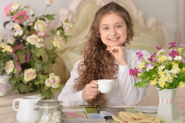 Portret van een mooi meisje dat thuis thee drinkt