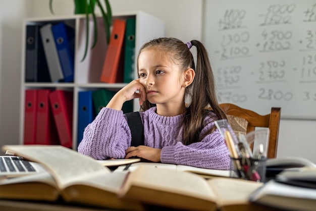 Portret van een mooi meisje in de klas aan een bureau met boeken en schoolspullen