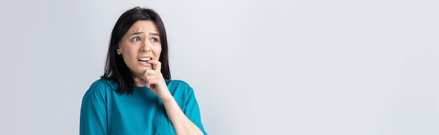 Portret van een mooi meisje in een blauwe t-shirt kijkt opzij met peinzende uitdrukking en overweegt een plan voor verdere actie