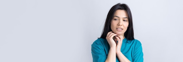 Portret van een mooi meisje in een blauwe t-shirt kijkt opzij met peinzende uitdrukking