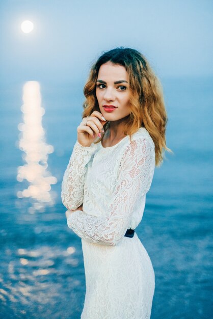 Portret van een mooi meisje in een witte jurk op het strand
