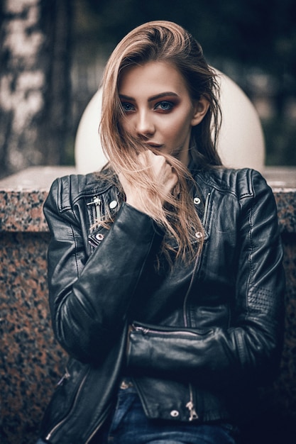 Portret van een mooi meisje in een zwart lederen jas
