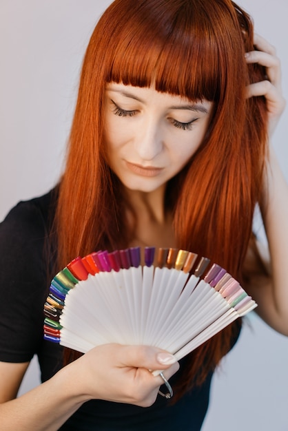 Foto portret van een mooi meisje met monsters van gekleurde nagellak. manicure