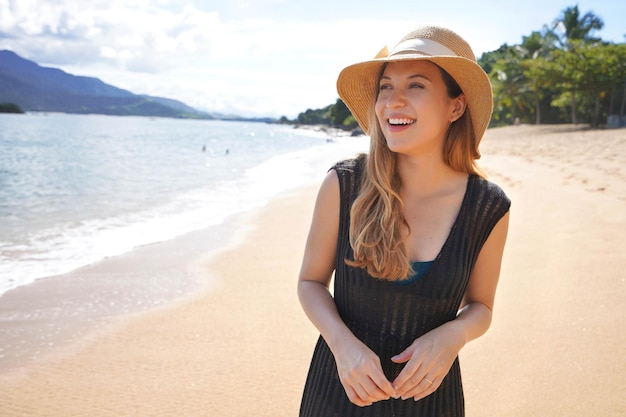 Portret van een mooi meisje met zomerjurk en strohoed op het tropische strand