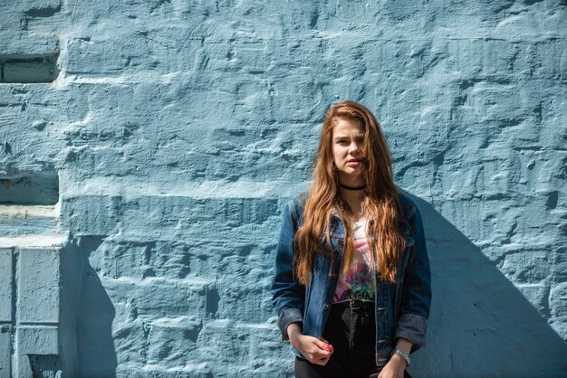 Portret van een mooi modern meisje tegen de blauwe bakstenen achtergrond
