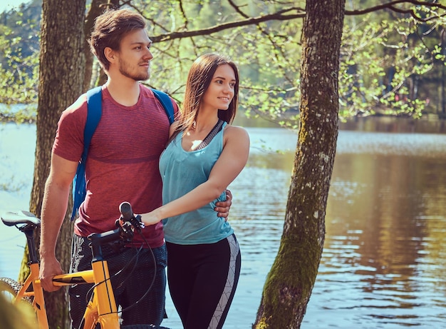 Portret van een mooi paar. glimlachend paar ontspannen terwijl ze bij het meer in het bos staan.