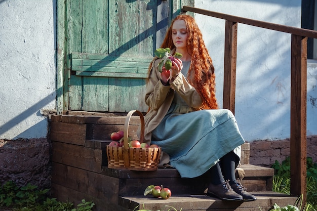 Portret van een mooi roodharig meisje met lang haar met appels in de herfst